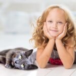 Enfant allongée avec son chat gris - Relation enfant-animal